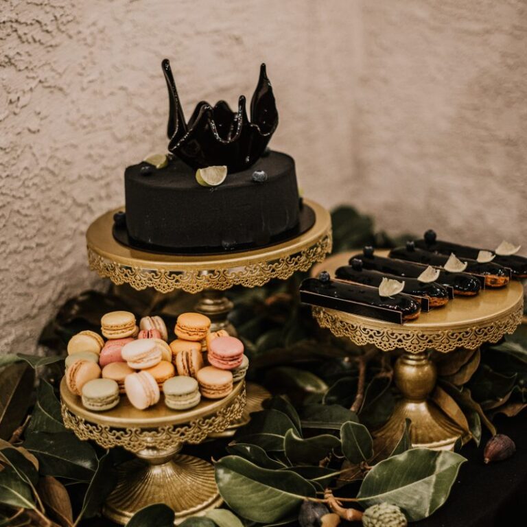 Dessert table with a black cake and macarons