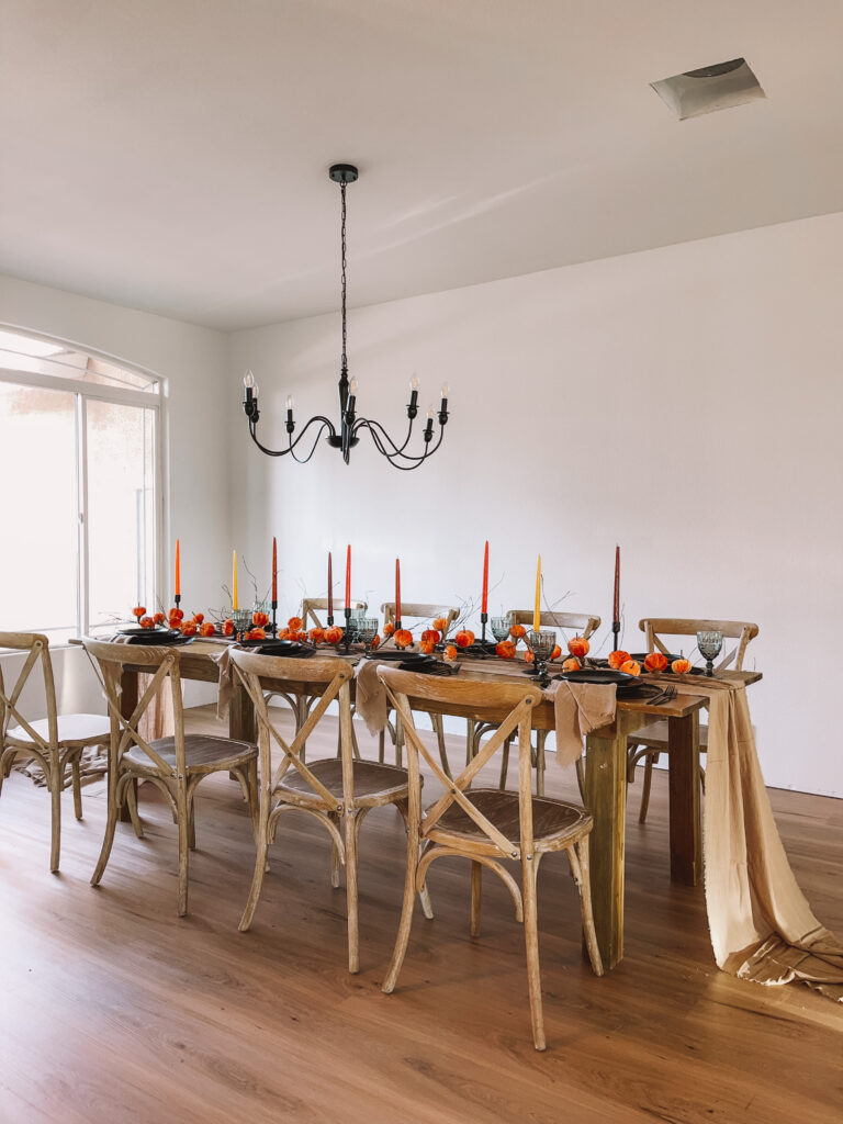 Long dining table with cross-back chairs under a chandelier